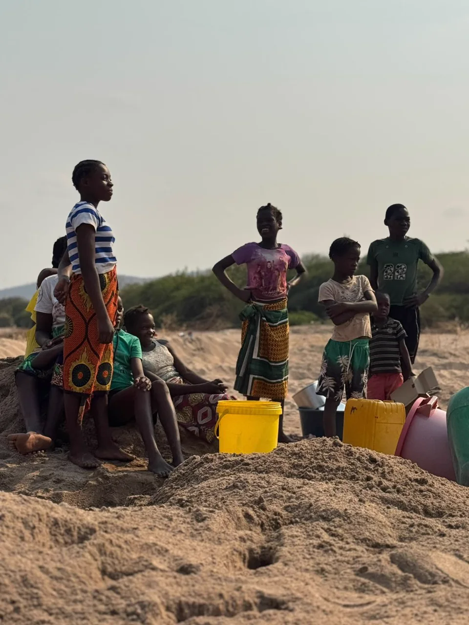 Familias junto a recipientes para recoger agua en Tete, Mozambique