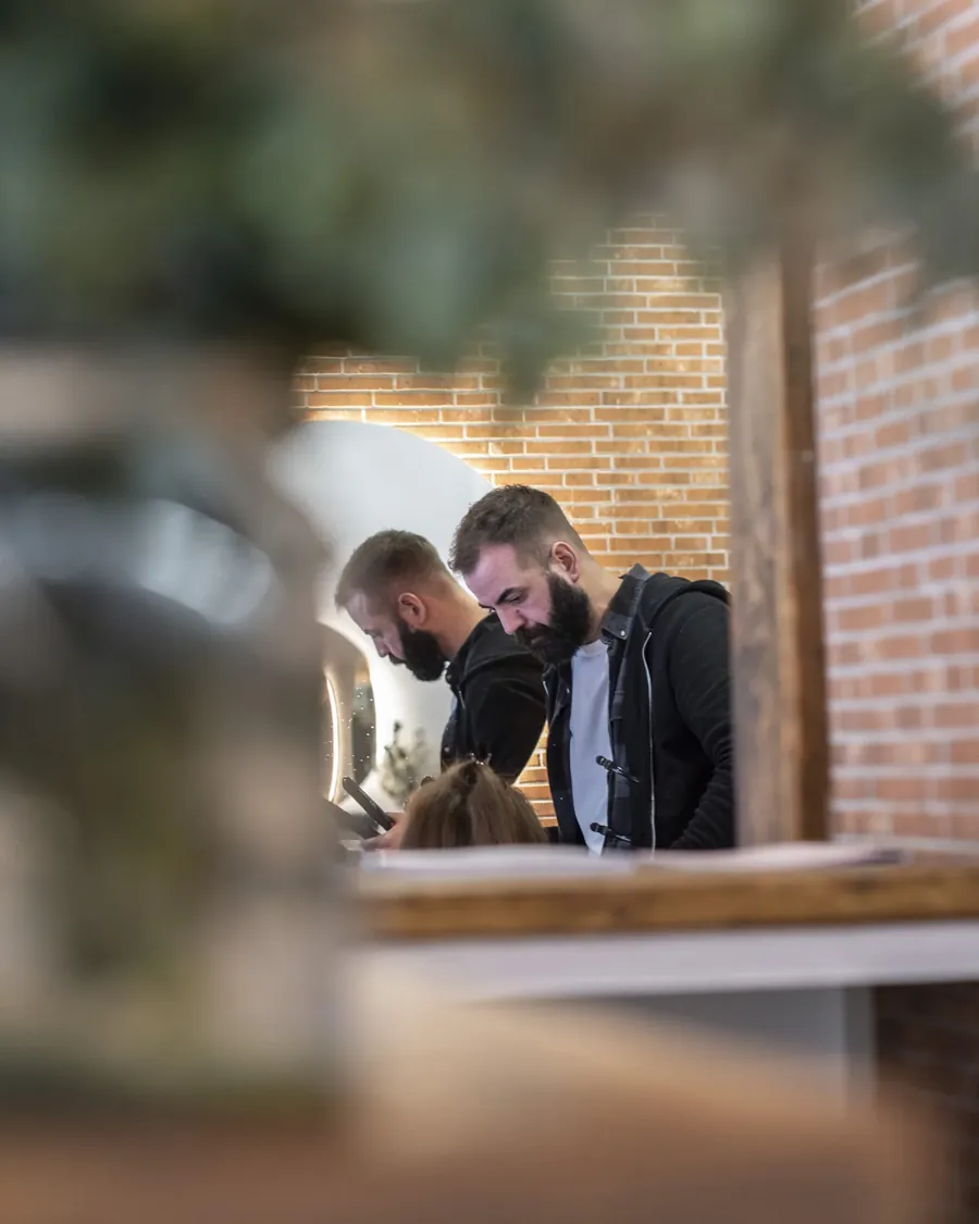 Dos peluqueros del equipo trabajando con una clienta en el salón de Vigo