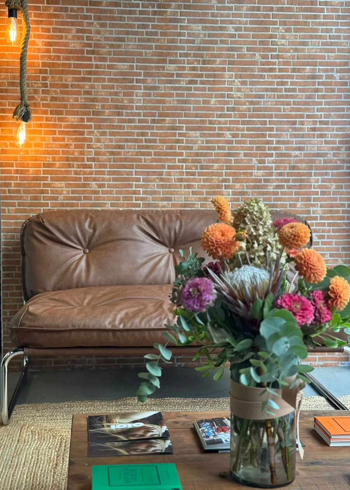 Sofá de piel, flores de temporada y libros en el salón de La Urbana en Vigo