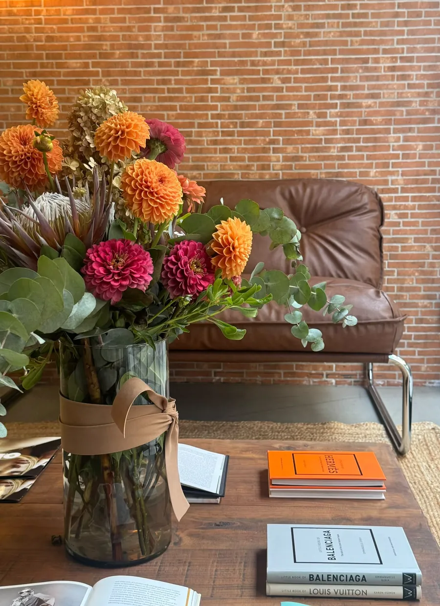 Rincón de espera de La Urbana con flores, sofá de piel y libros