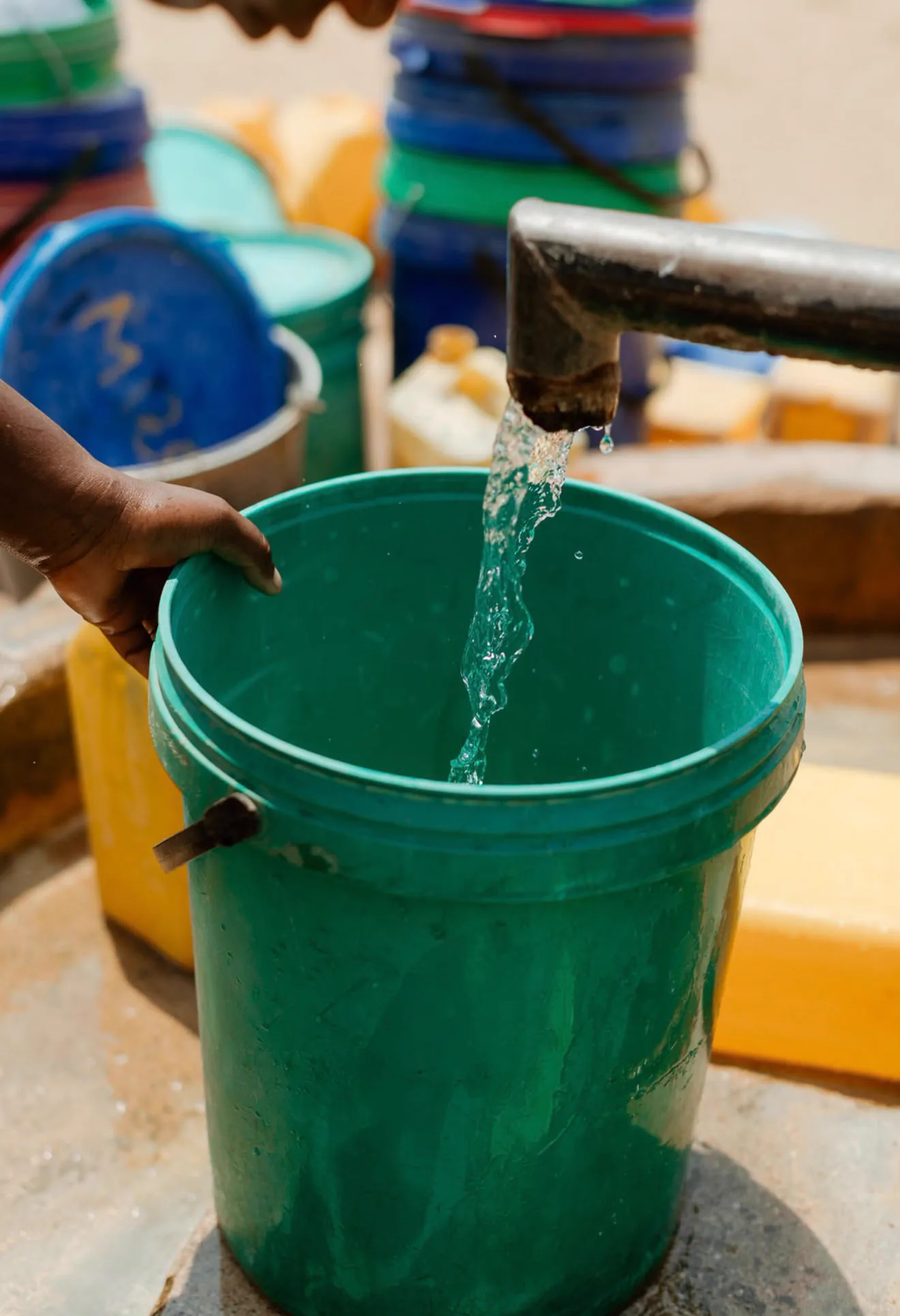 Agua fluyendo hacia un cubo verde durante la visita en Tete
